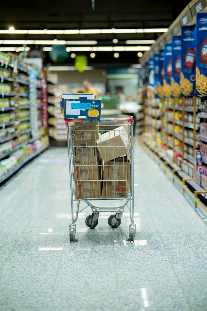 home-hero-2 A shopping cart with packages in a grocery aisle, showcasing everyday shopping options.